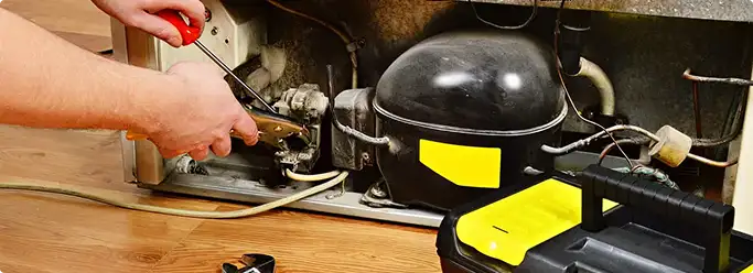 Refrigerator repair technician fixing the compressor and wiring in Sun Prairie, WI