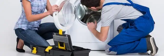 Washer repair technician inspecting a front-load washing machine with tools in Madison, WI