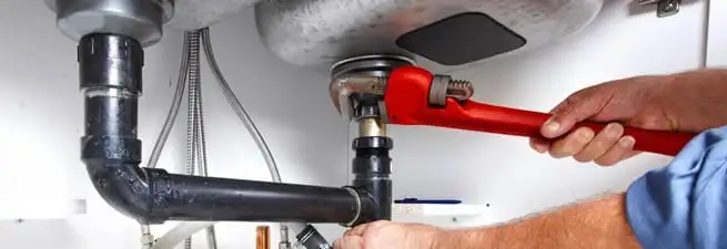 Garbage disposal repair technician tightening the sink drain and disposal connection in Madison, WI