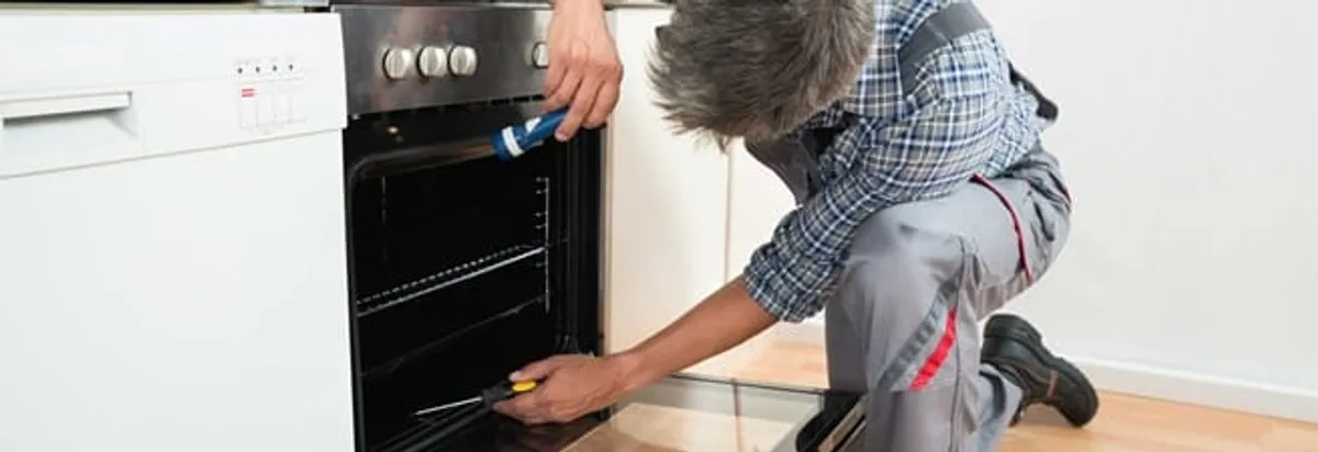 Oven repair technician inspecting and servicing an electric oven in Madison, WI