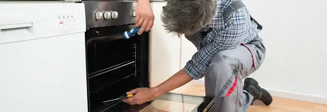 Oven repair technician inspecting and servicing an electric oven in Madison, WI
