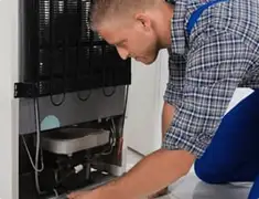 Refrigerator repair technician servicing the compressor and condenser area in Madison, WI