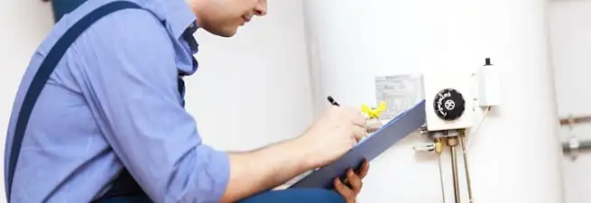 Water heater repair technician inspecting the unit and recording service notes in Madison, WI